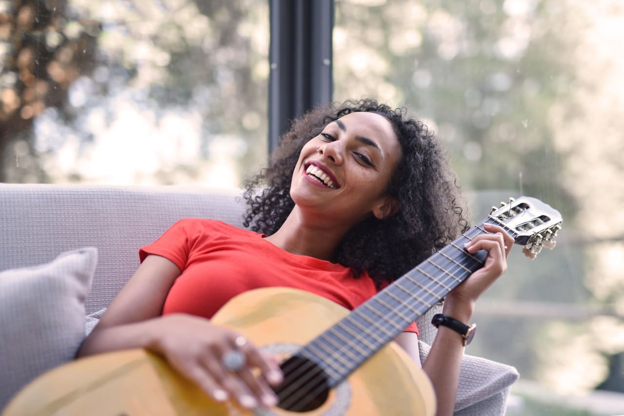 A woman in red shirt, playing a guitar | dentist in Denham Springs