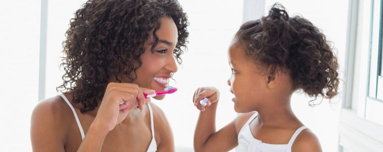 A mom and daughter brushing their teeth